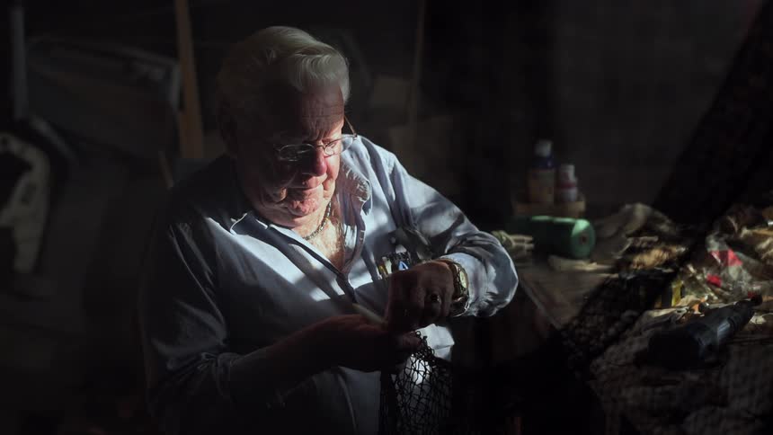 A man is sitting at a table working on something in the dark