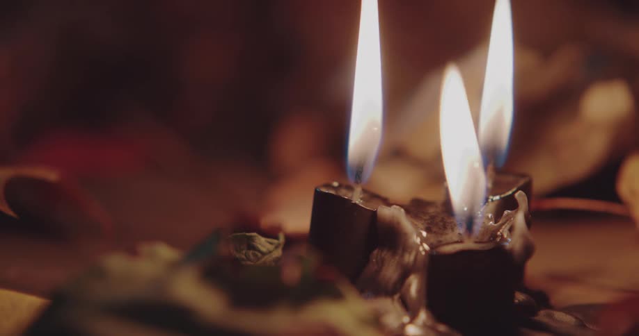 Three candles are melting under bright flames