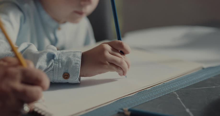 A child is drawing at the kitchen table indoors