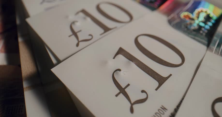 Text on british banknotes lying in a pile on a table