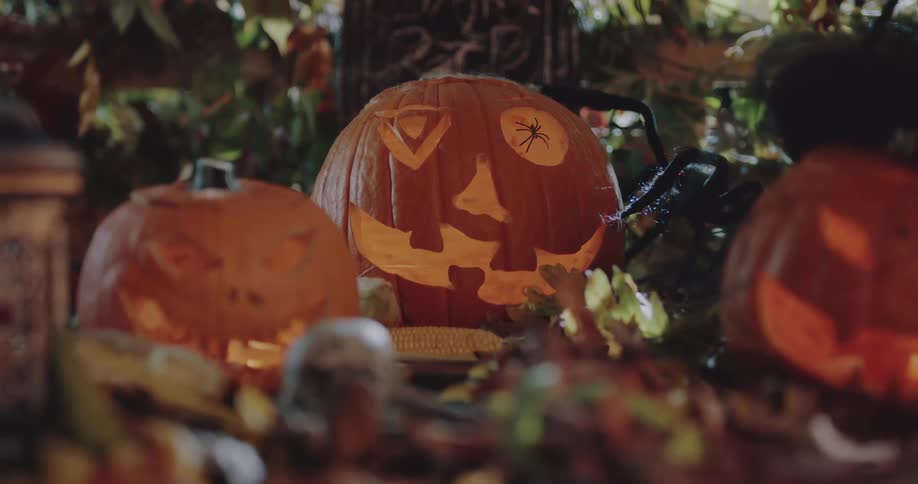 Carved pumpkins and a lantern are lit at night