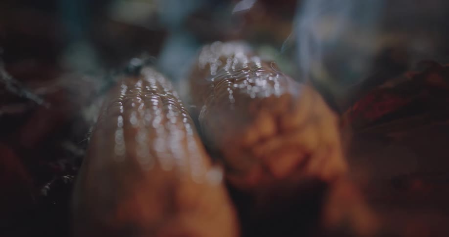 Vapor rises off the ground wafting over two corn cobs lying on the ground