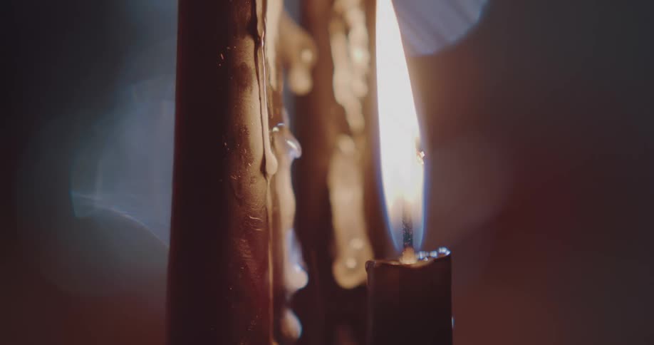 A flame on a candle is burning and melting candle wax