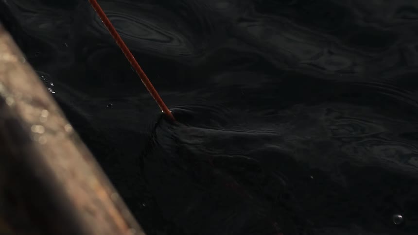 Off the side of a boat a pole is in the water