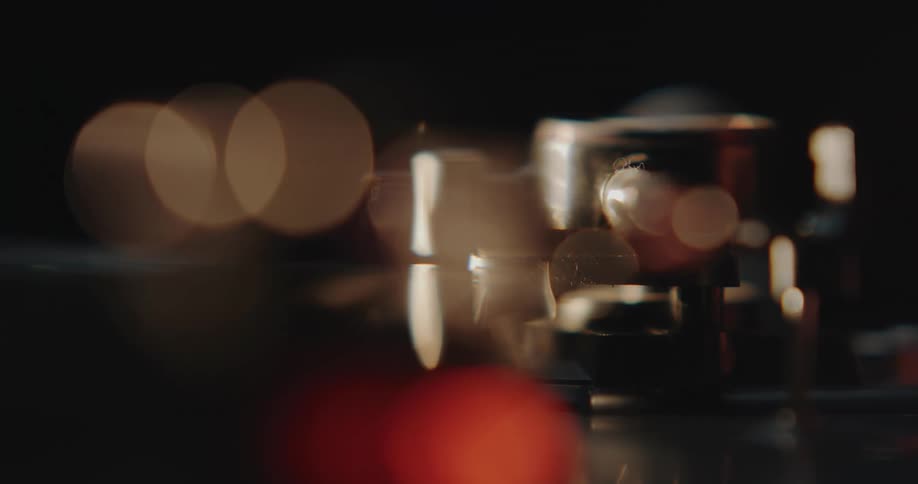 Close up of the arm of a turntable slowly lowering down over a spinning vinyl record