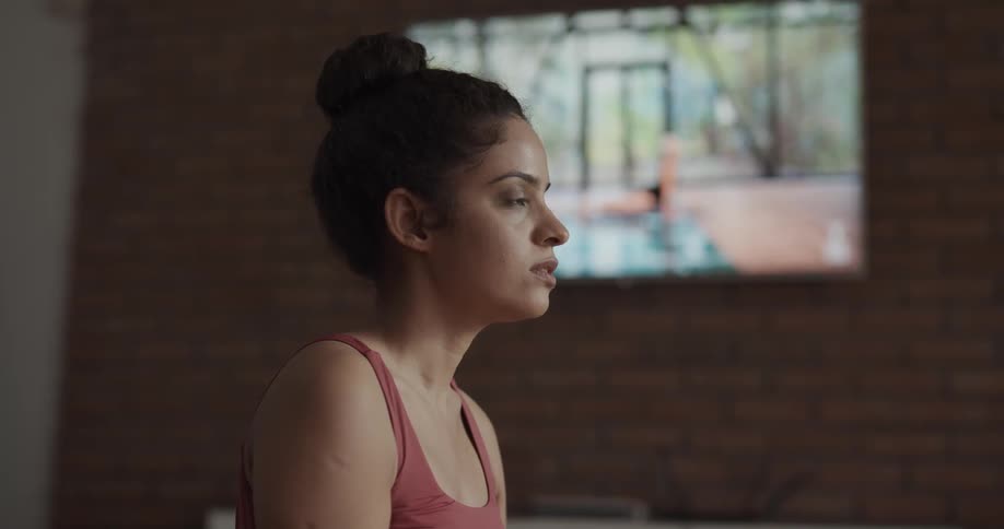 A young woman practices yoga on a mat indoors