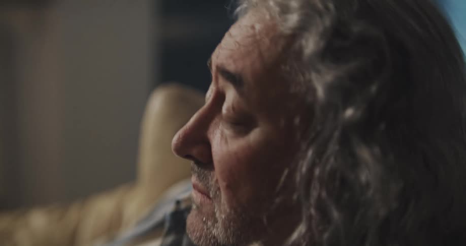 A drunk man is sitting in a chair and drinking an alcoholic beverage from a glass