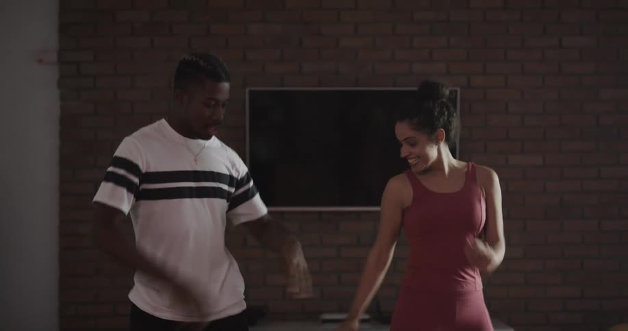A man or a woman are dancing on hardwood floor in a living room