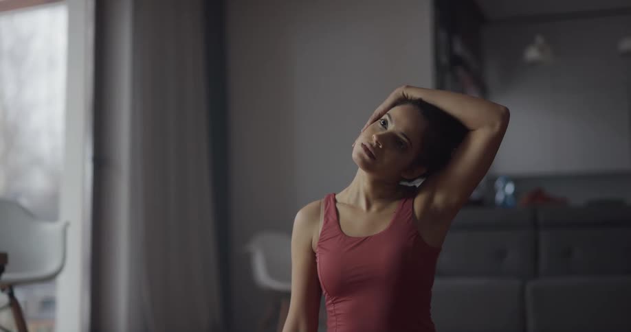 A woman practices yoga in the living room of a house during the day