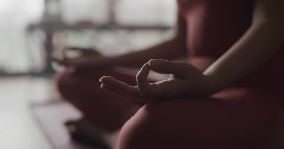 A woman is doing yoga while sitting on a floor indoors