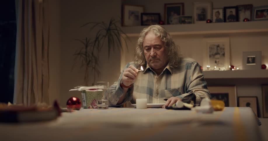A man lights a small candle while sitting down for dinner