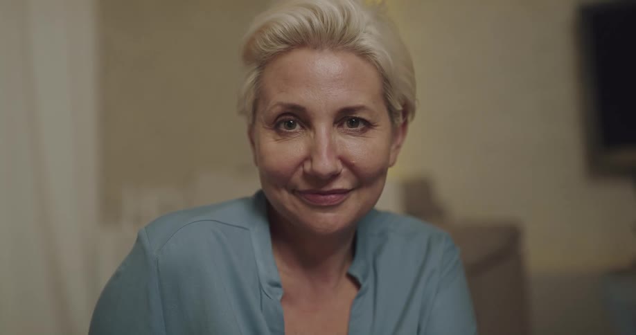 A woman is sitting indoors and smiling
