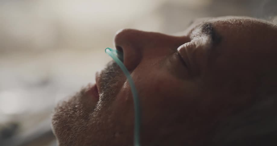 A man is sleeping with a breathing tube in his nose