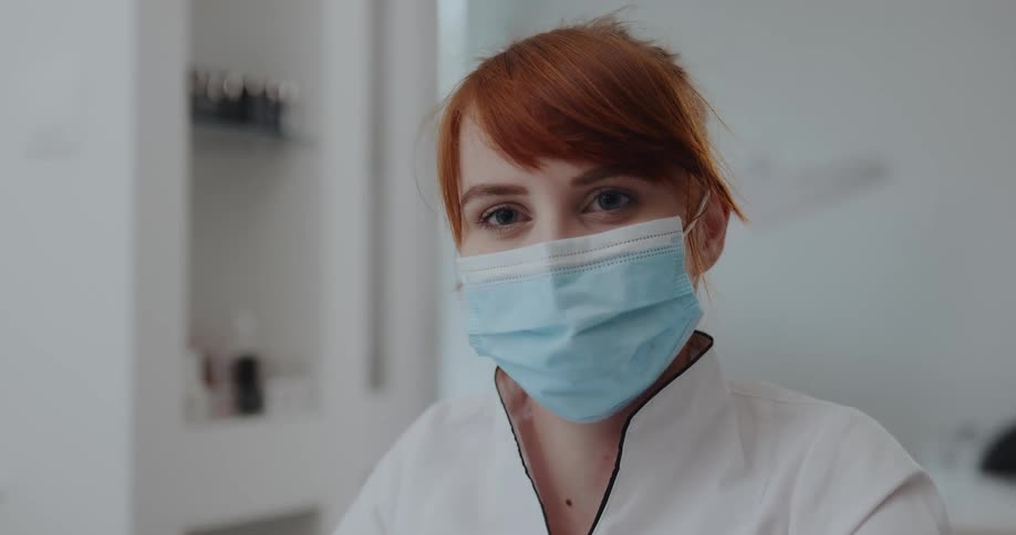 Female red head wearing a face mask looking up to the camera