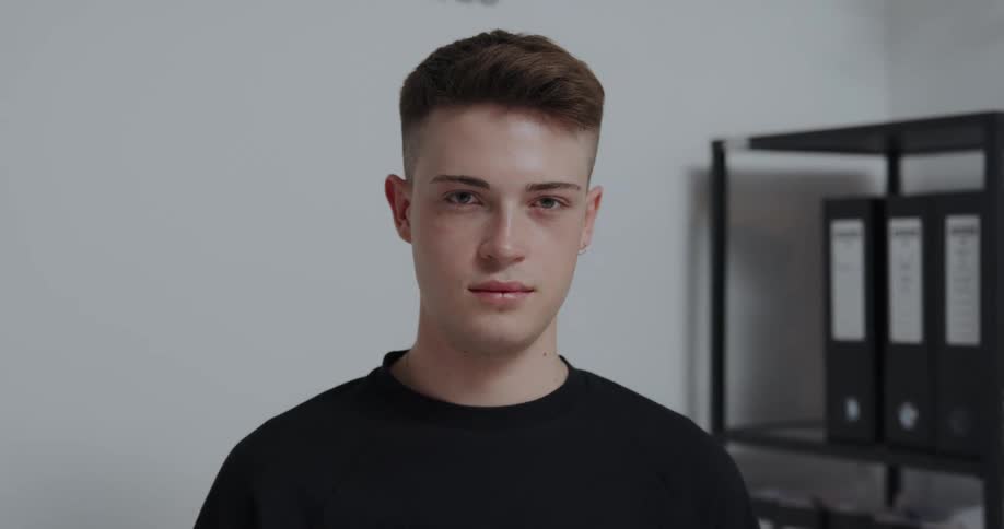 Man with crew hair cut and black t shirt looks at camera in the office
