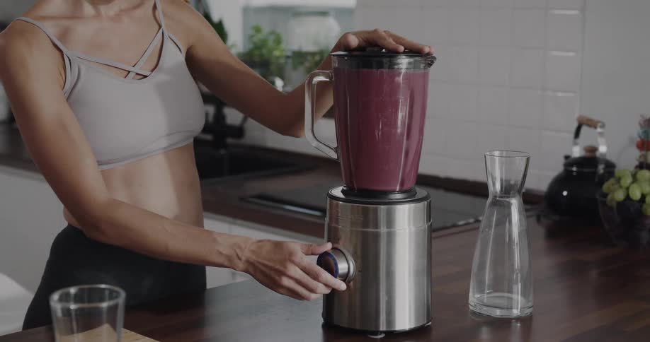 A woman is making a smoothie at home during the daytime