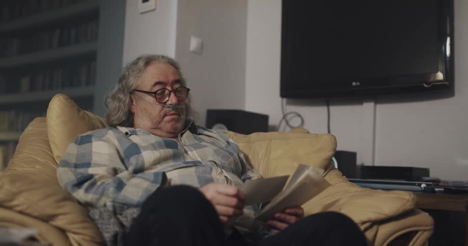 Man sitting on a couch at home looking at old black and white photos