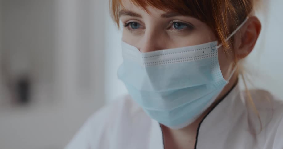 Redheaded woman wearing face mask and gloves works