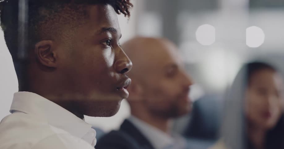 A man speaks while sitting at a conference table in a meeting with coworkers