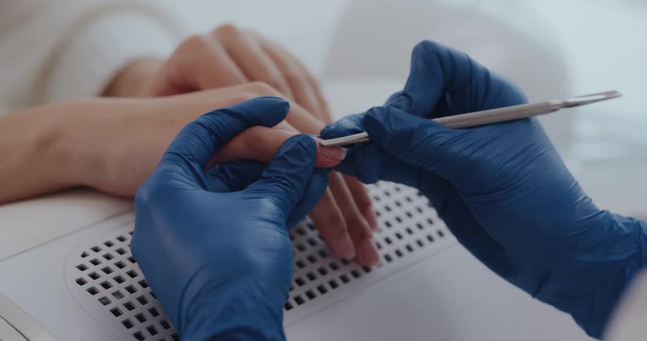 A nail technician opens a stainless steel tool to work on a customers nails