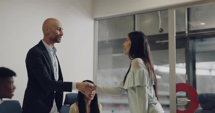 An interview ends with a woman shaking hands of the people who work in the office