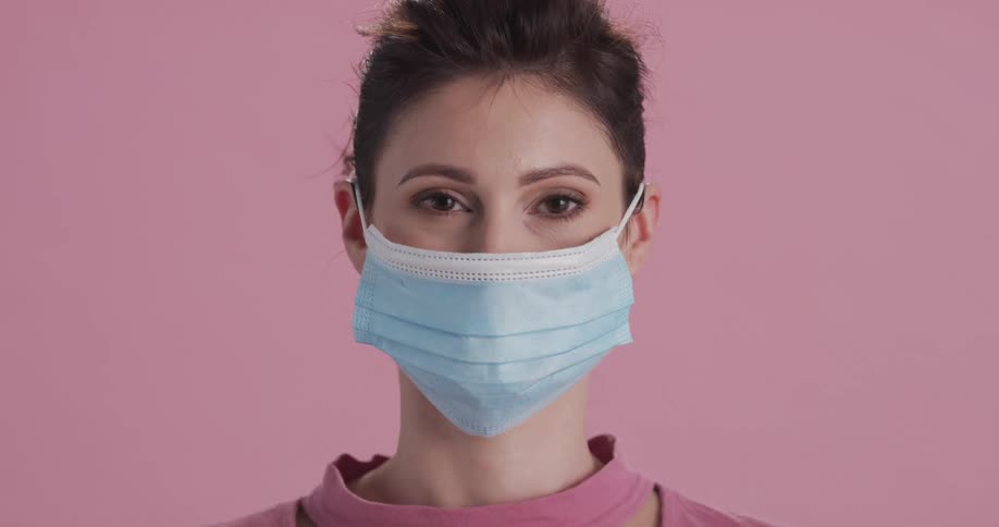 A portrait of a woman putting on a face mask