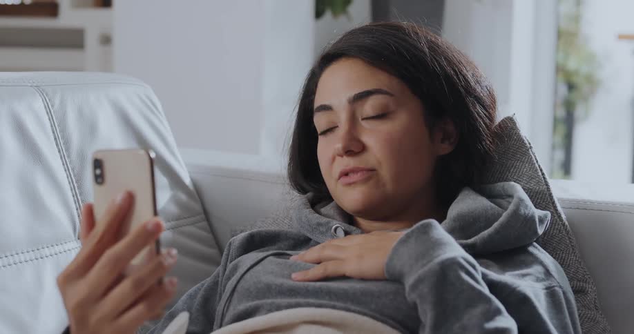 Young woman is laying down and talking on the phone