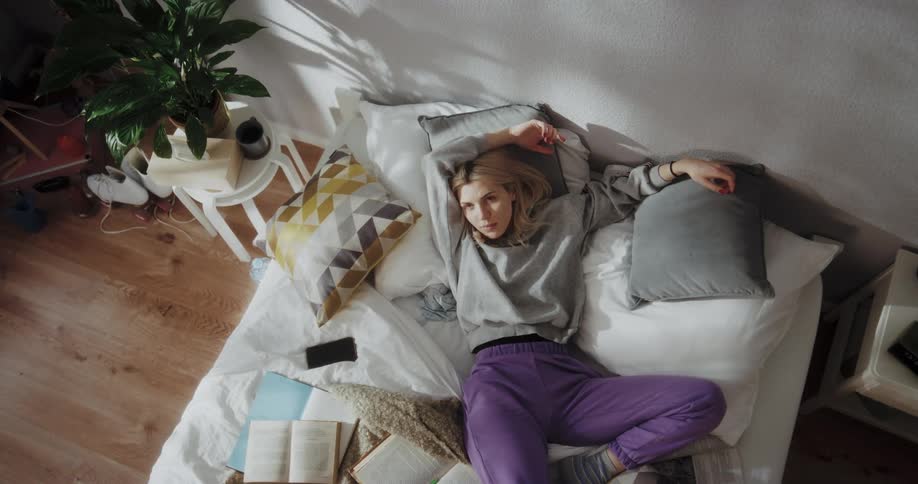 Young blonde woman laying in bed on her bedroom at home