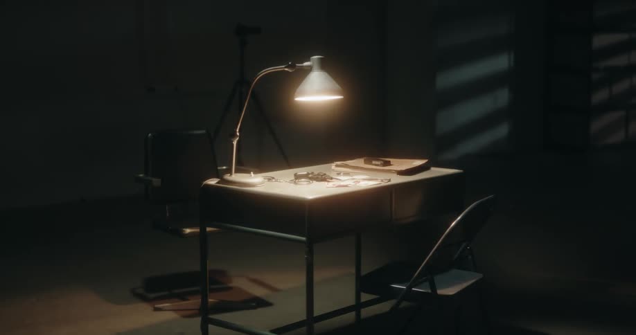 A table lamp flickers in a police interrogation room