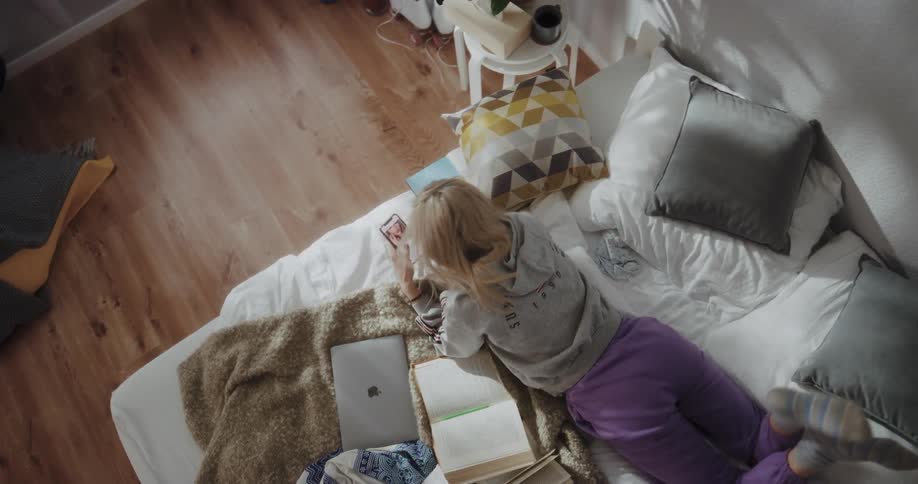 Young blonde woman is laying on her bed