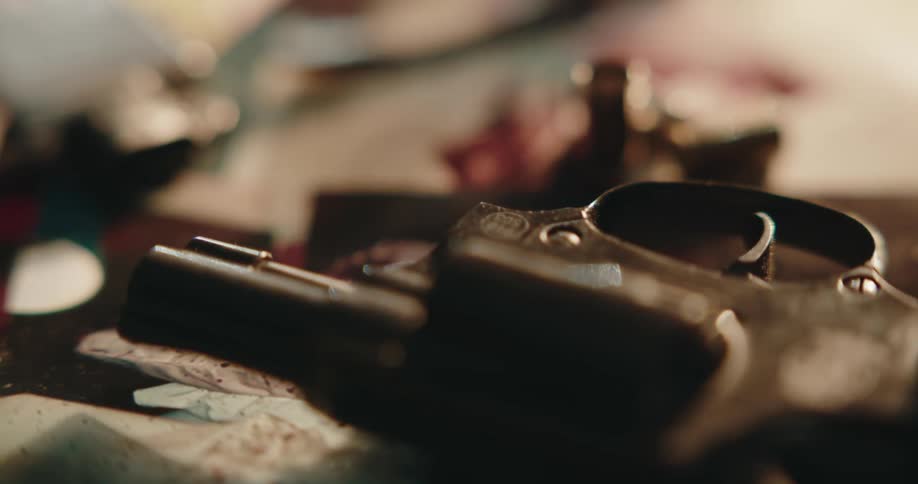 A rusted pistol sits on top of photos on a table