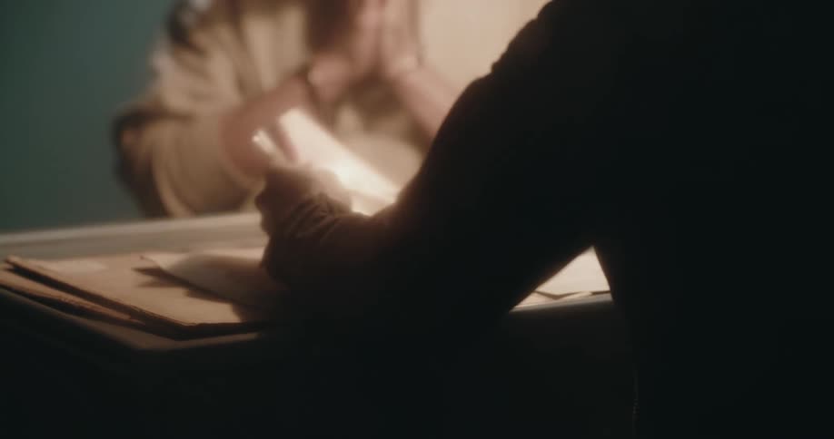 Detective shows pictures to a suspect sitting inside an interrogation room