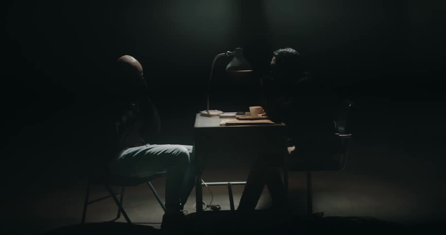 Detective interviewing a suspect on a dimly lit interrogation room
