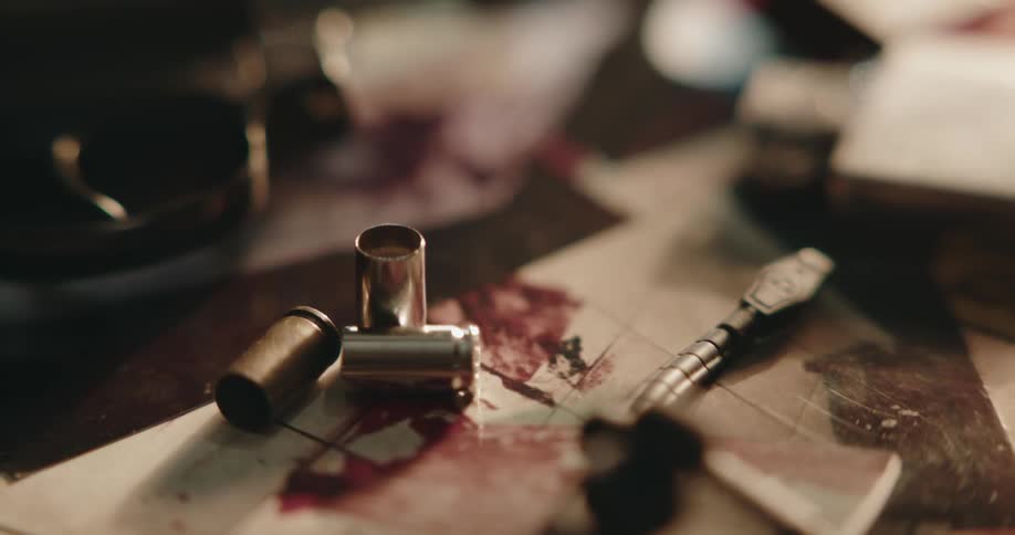 A revolver and bullet casings resting over photographs of a crime scene on a desk