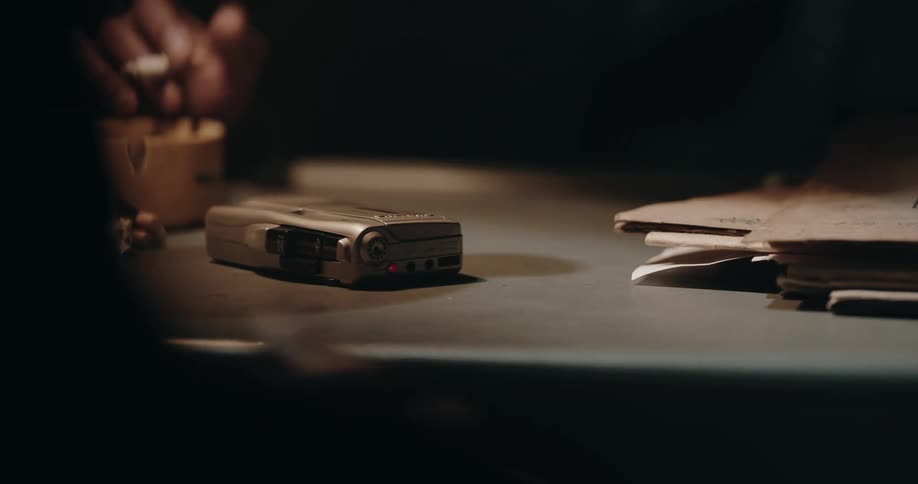 Men talking around a desk with a tape recorder and files over it