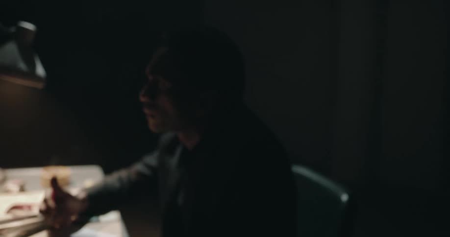 Man interrogates suspect sitting on a chair inside an interrogation room