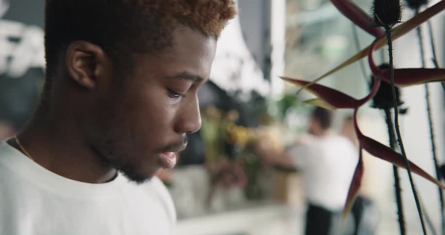 Young man working on a flower shop smells exotic plants