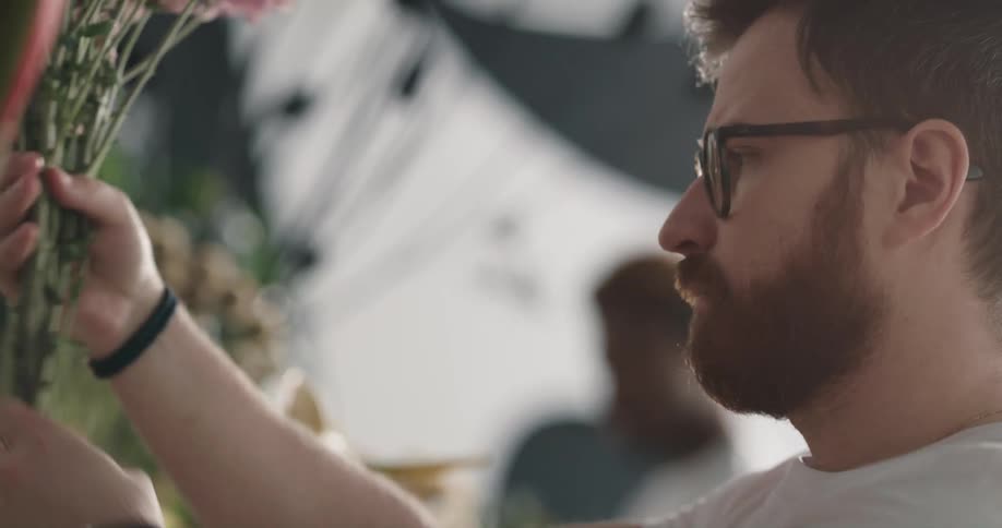 Redheaded man selects flowers at floral shop