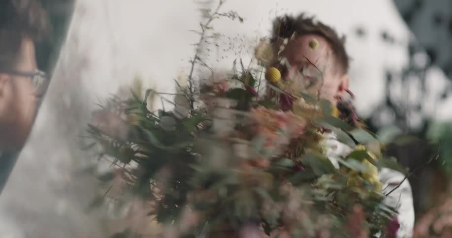 A florist discusses and lifts up a bouquet to hand to a colleague
