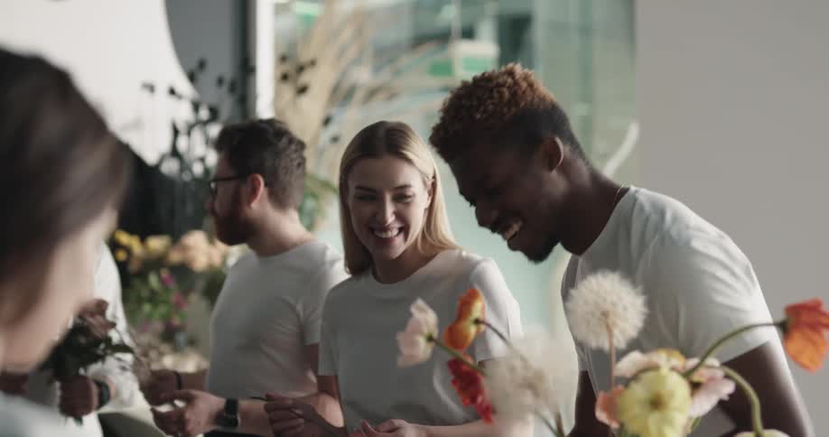 A man and woman laugh while working on bouquets at a florist