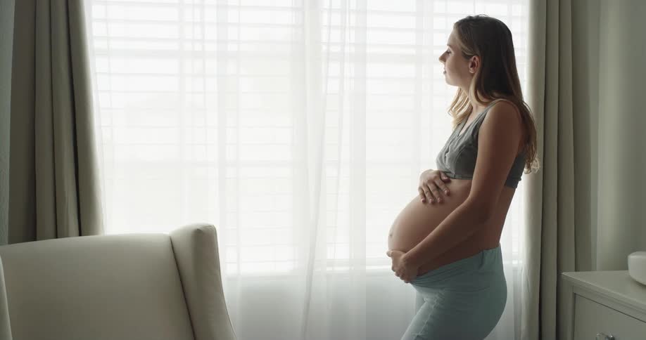 Pregnant mother gently rubs and massages her belly with both hands