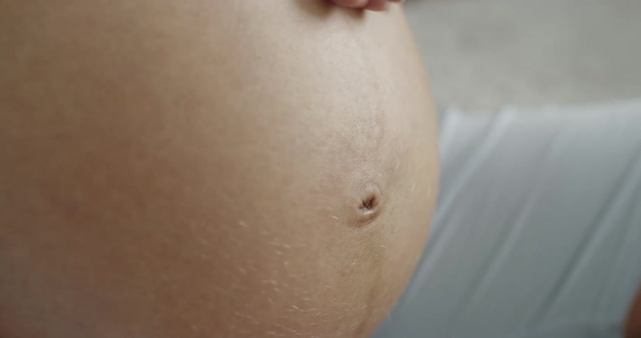 Pregnant mother gently rubs and massages her belly with her hand