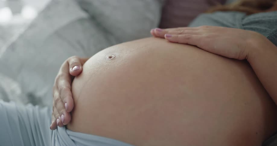 Pregnant mother gently rubs and massages her belly with both hands