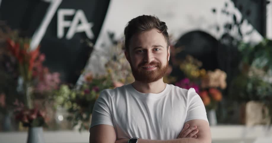 Young man is standing in front of some flowers
