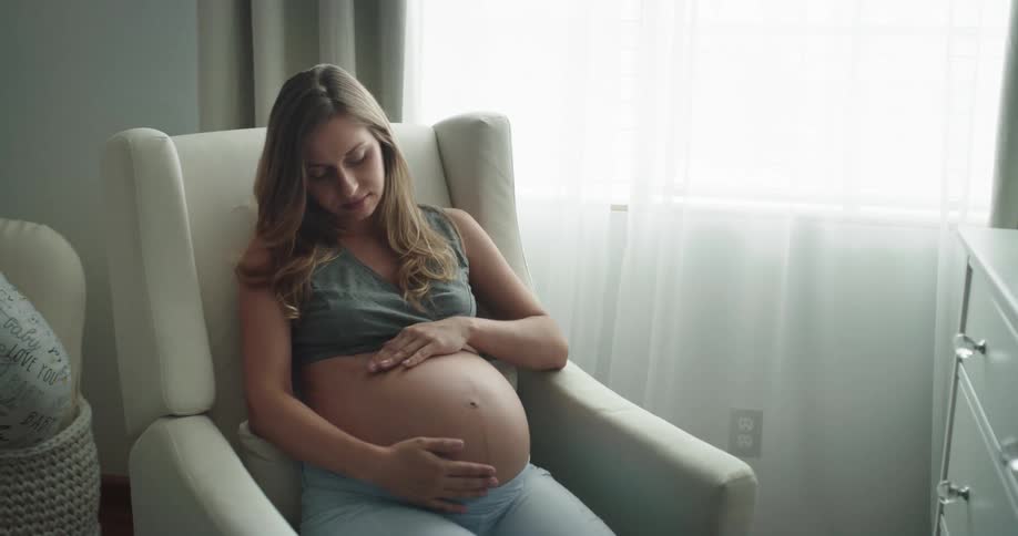 Young pregnant woman is rubbing her belly