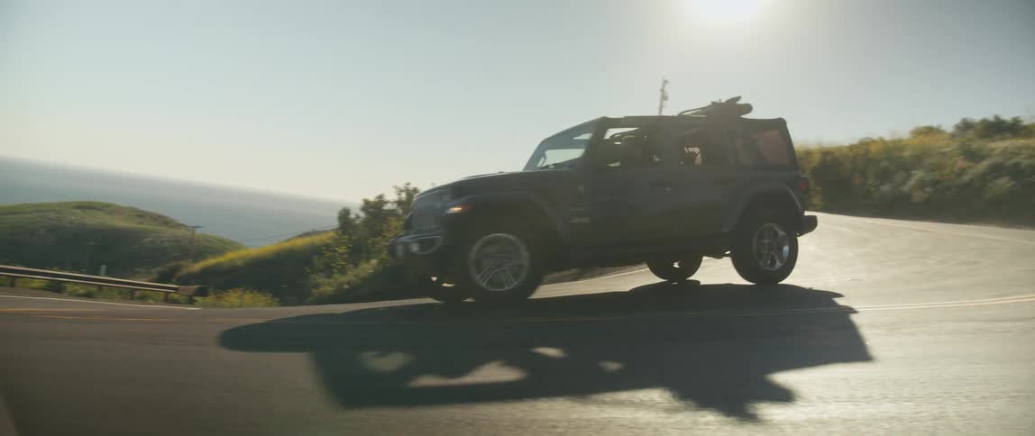 A man drives a vehicle along a winding road on the coast during the day