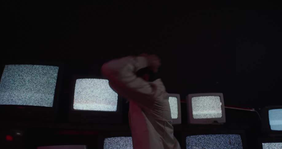 Angry man lashes out in front of a row of vintage televisions showing static on their screens