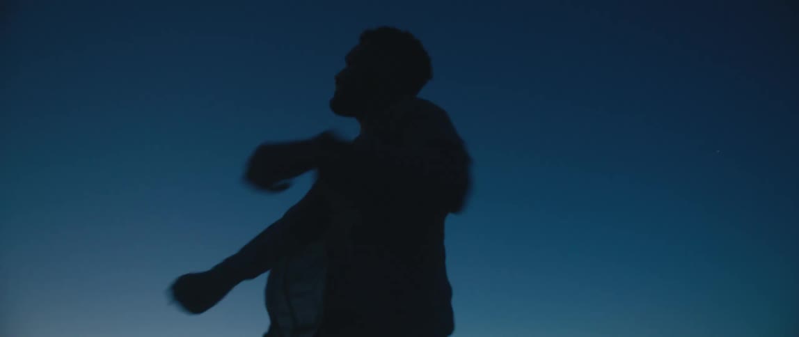 A man is outdoors and putting on a coat