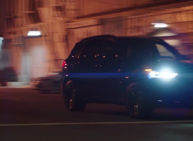 A vehicle travels along a road through a city at night