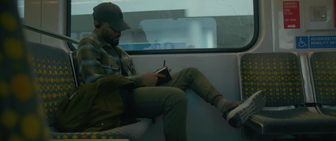 A man writes in a notebook while riding public transportation